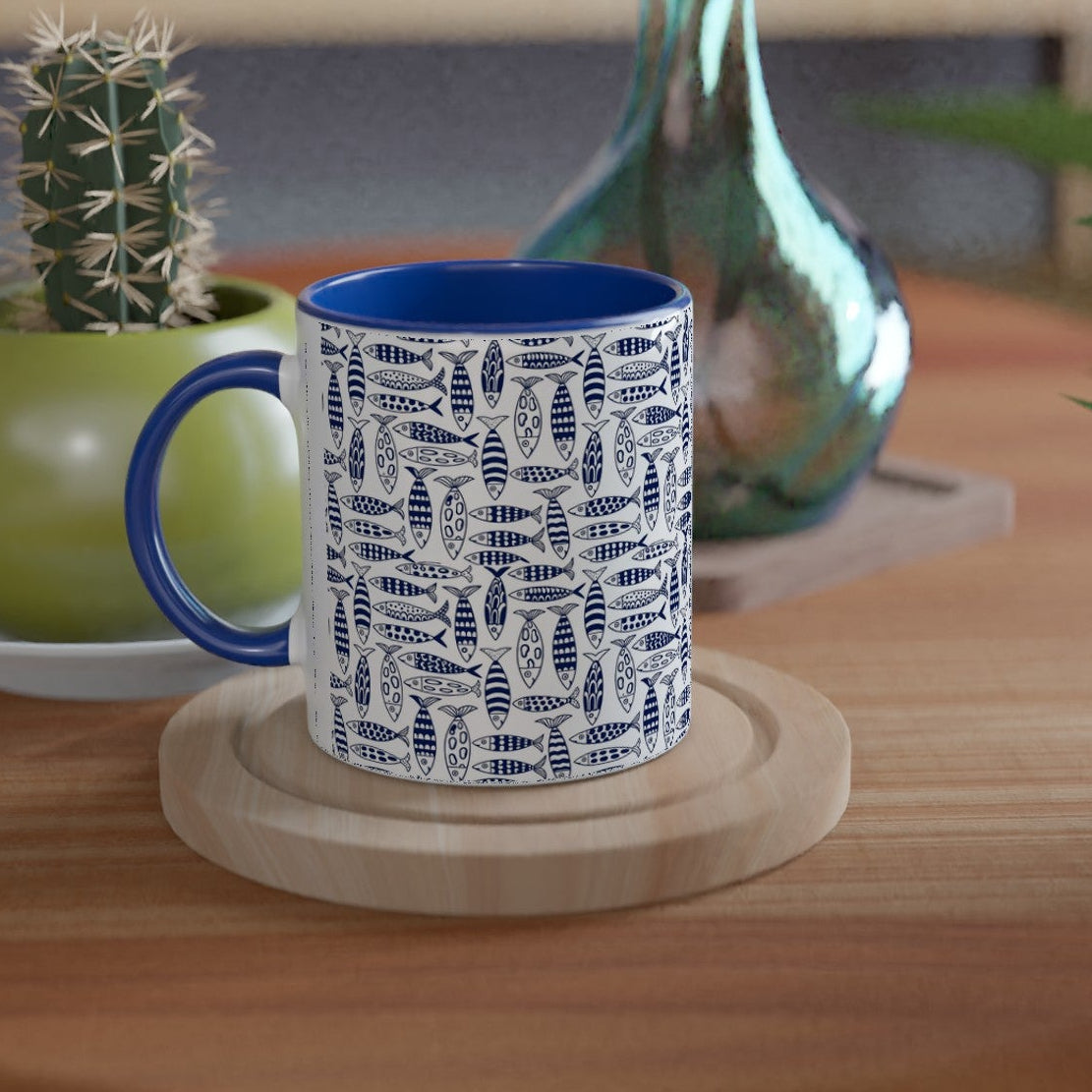 Blue mug with white pattern on a wooden table with plants and a vase.