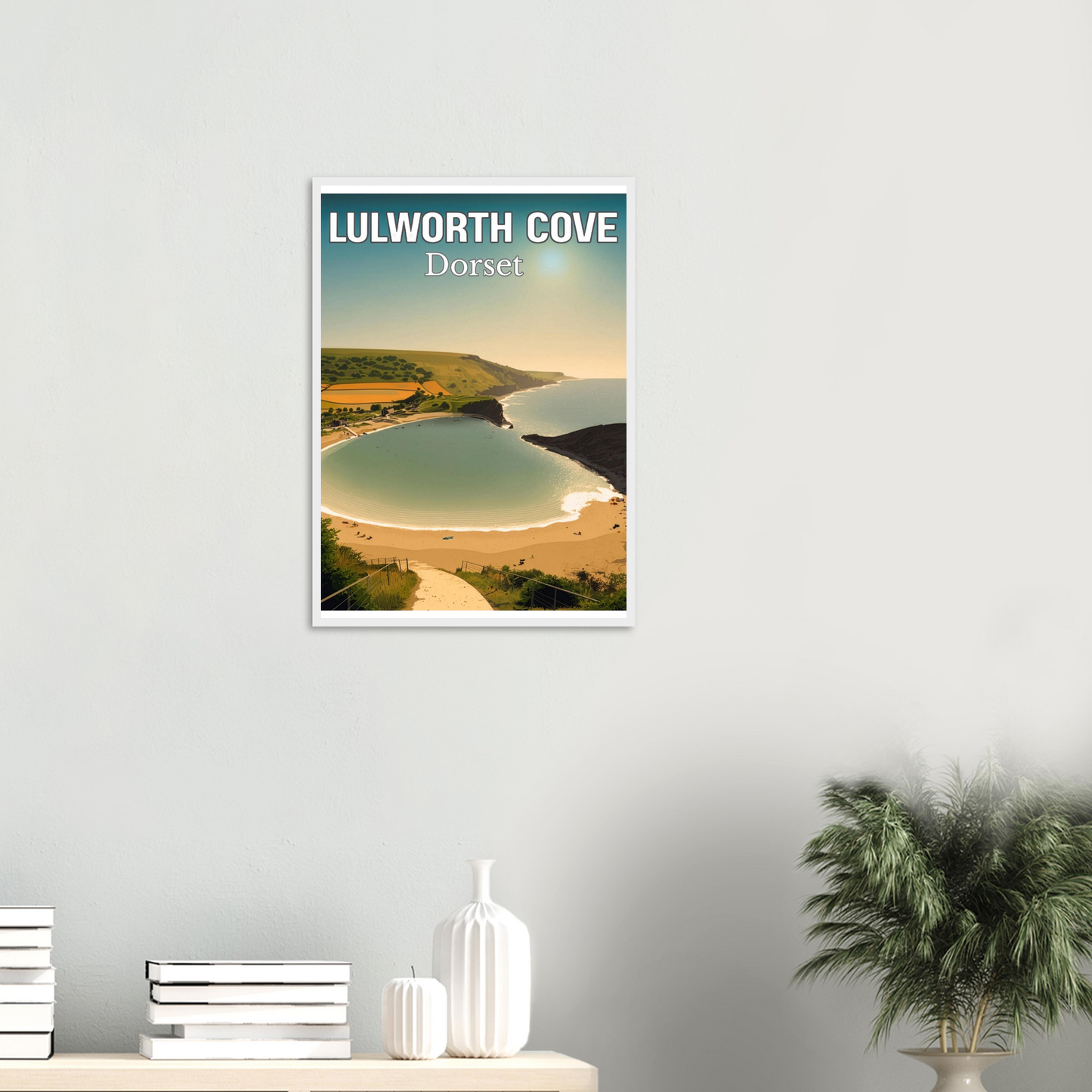Framed poster of Lulworth Cove, Dorset on a wall above a shelf with decorative items.
