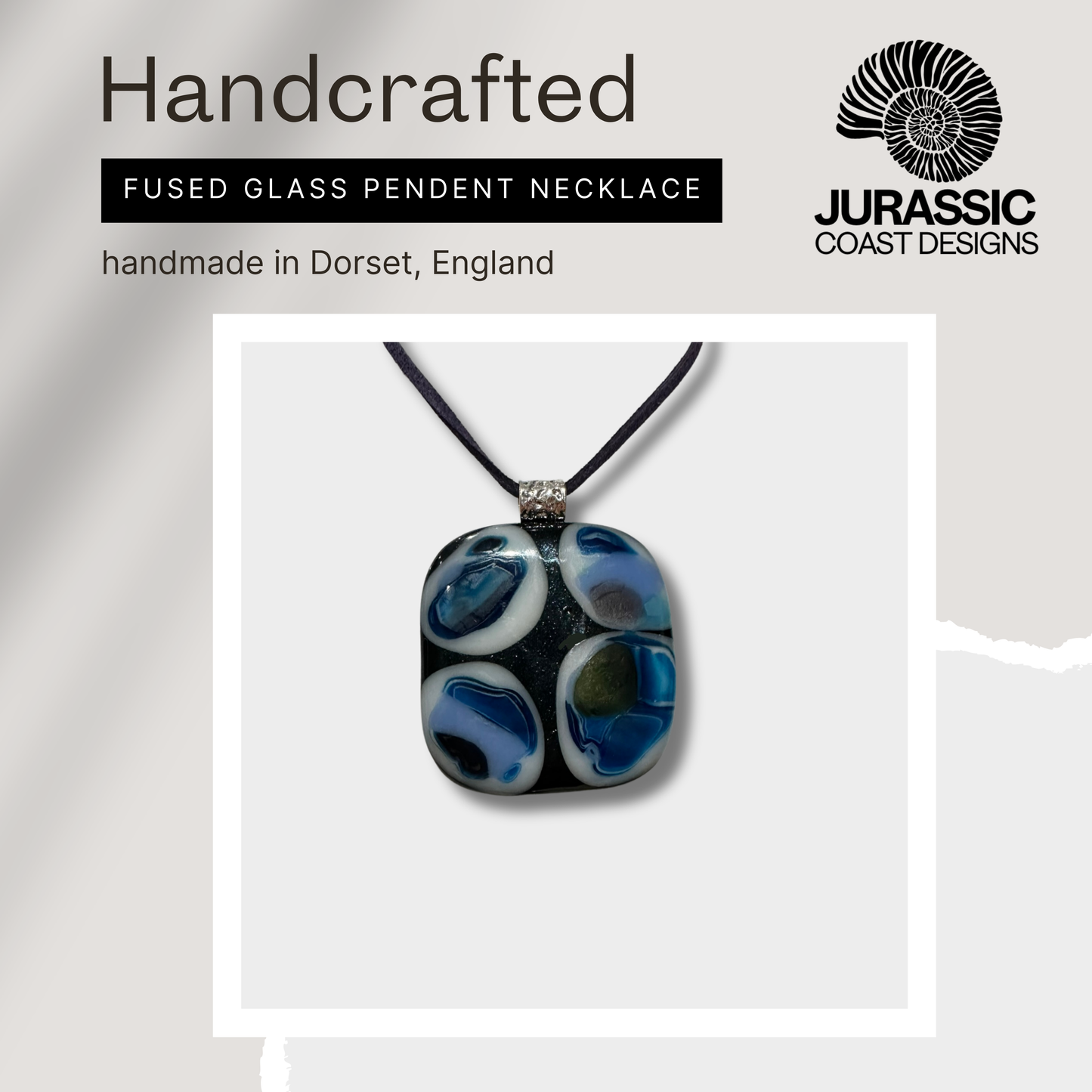 Handcrafted fused glass pendant necklace with 'Jurassic Coast Designs' branding on a light gray background.