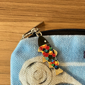 Pouch with 'In Pure Old Origin' text and a keychain on a light background