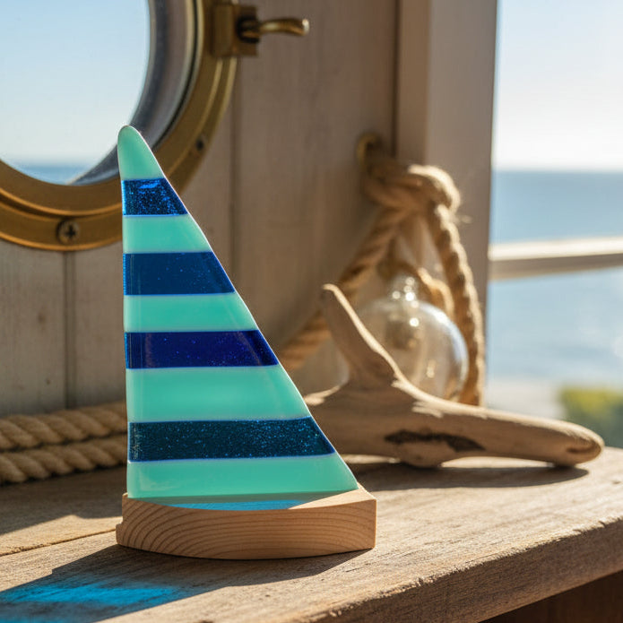Decorative glass sculpture with blue and green stripes on a white surface