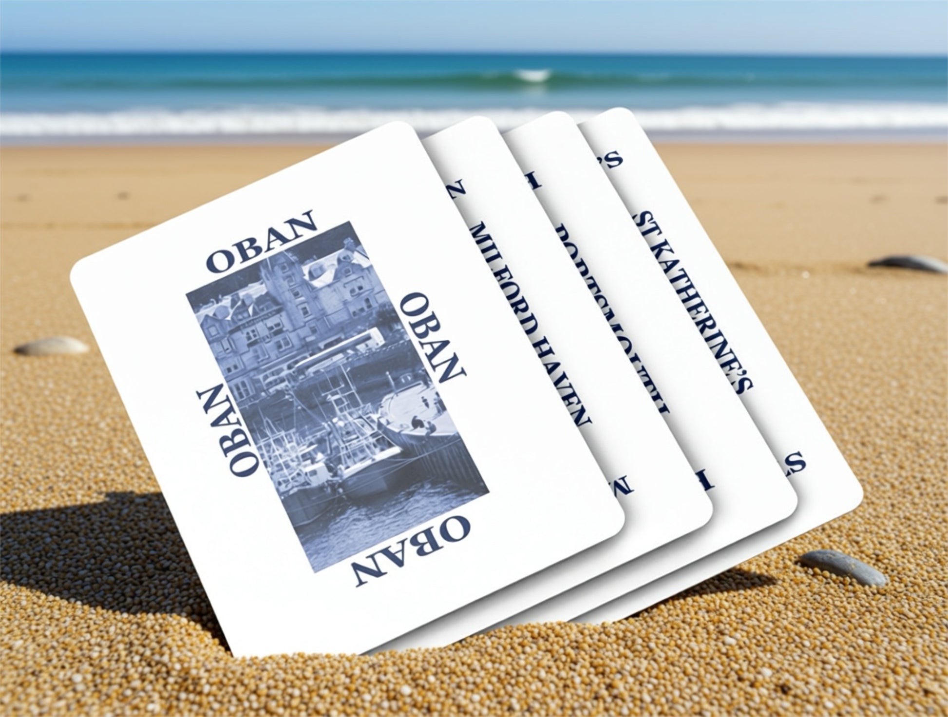Set of playing cards with 'Oban' and 'St Katherines' on a beach