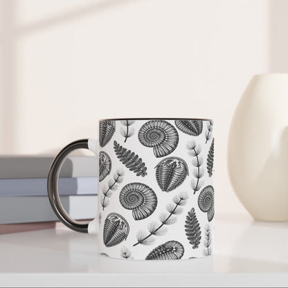Mug with black and white pattern on a white surface with books and decorative items.