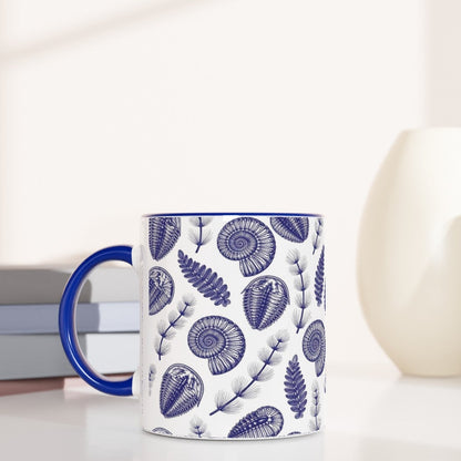 Mug with blue fossil pattern on a white surface with books and decorative items.