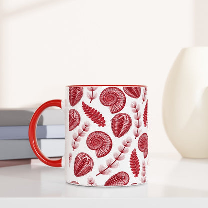 Mug with red fossil pattern on a white surface with books and decorative items.