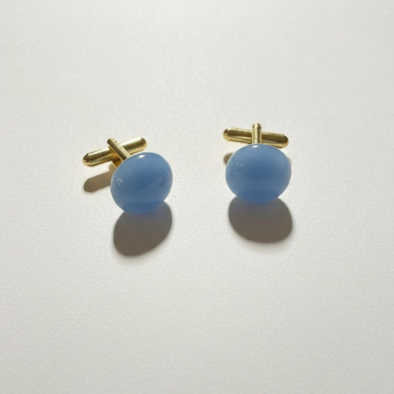 Pair of blue cufflinks with gold clasps on a white background