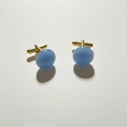 Pair of blue cufflinks with gold clasps on a white background