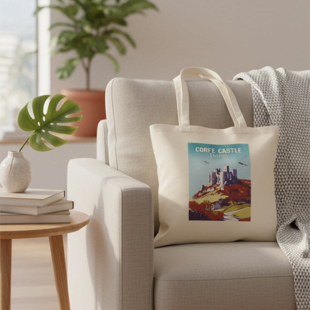 Corfe castle tote bag in a room with a beige armchair, decorative pillow, and framed pictures on the wall.