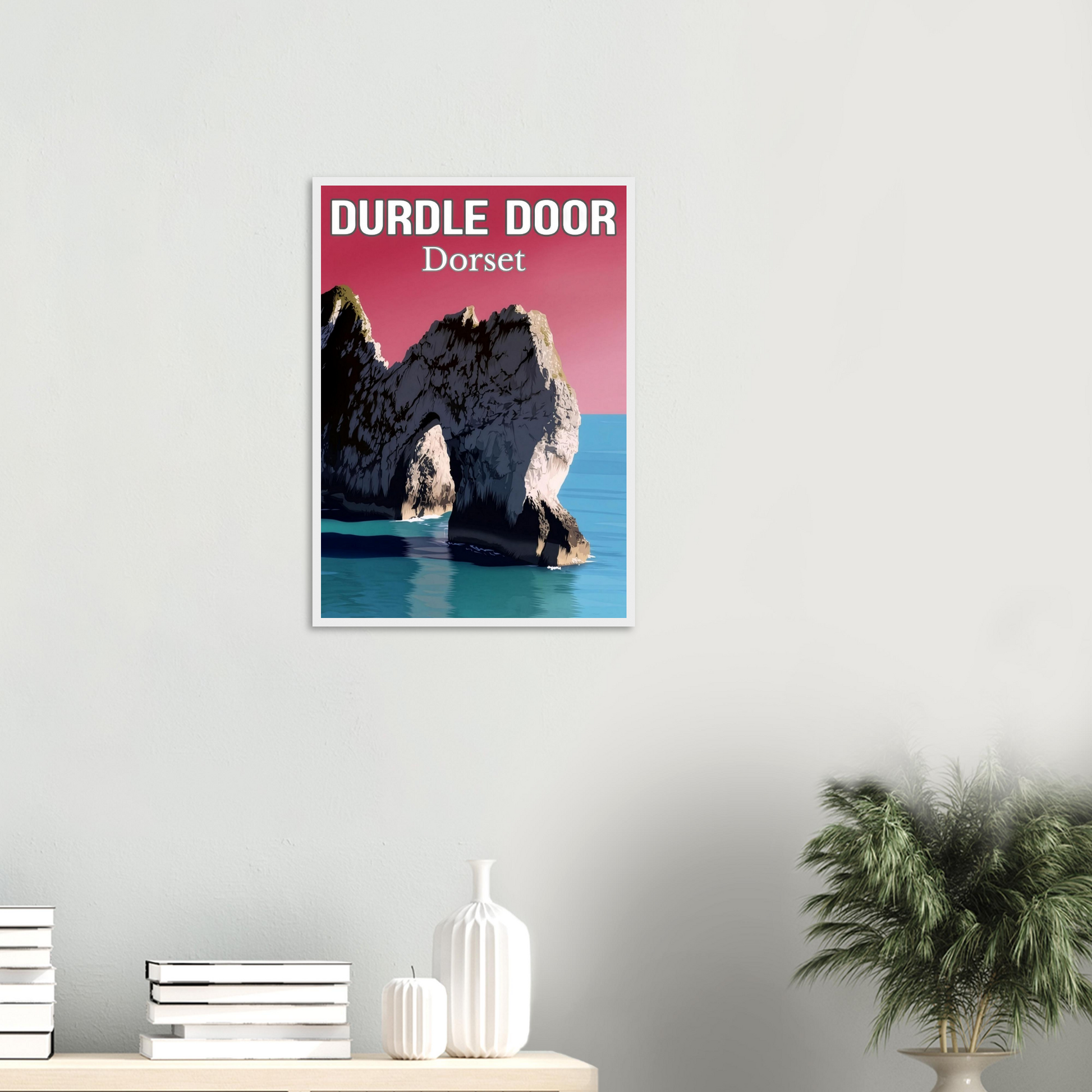 Framed poster of Durdle Door, Dorset on a wall above a shelf with decorative items.