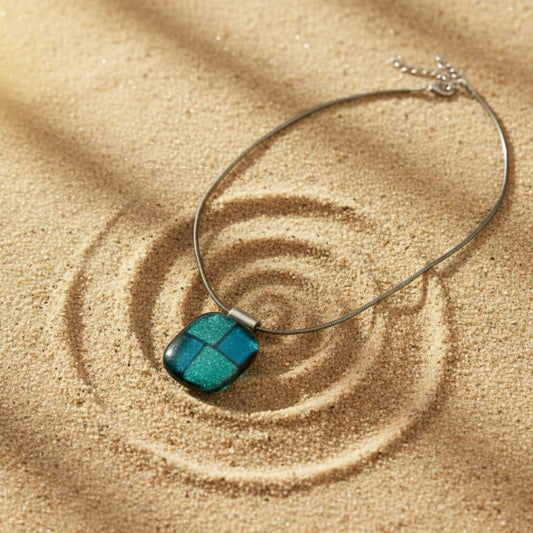 Necklace with a blue pendant on sand