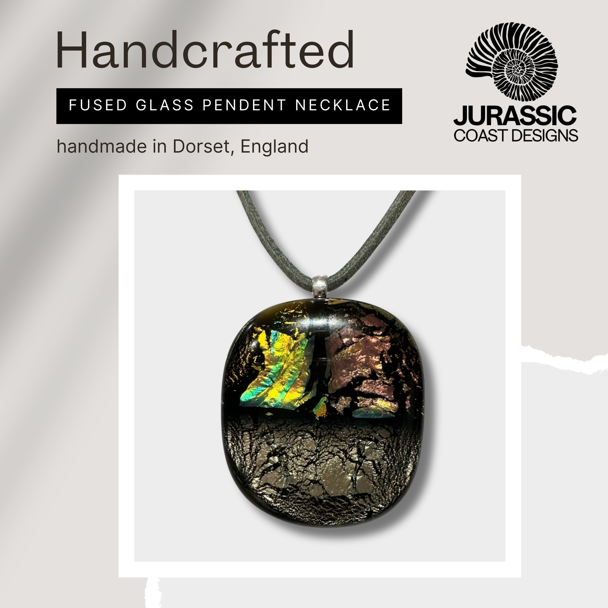 Handcrafted fused glass pendant necklace with 'Jurassic Coast Designs' branding on a light gray background.