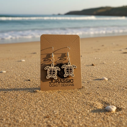 Turtle-shaped earrings on a 'Jurassic Coast Designs' card against a white background