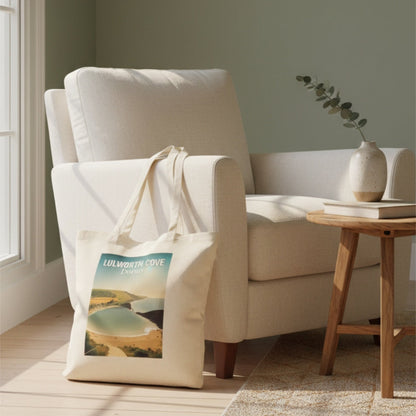 Lulworth Cove tote bad beside a white armchair with a tote bag on a wooden floor in a room with a window and small table.