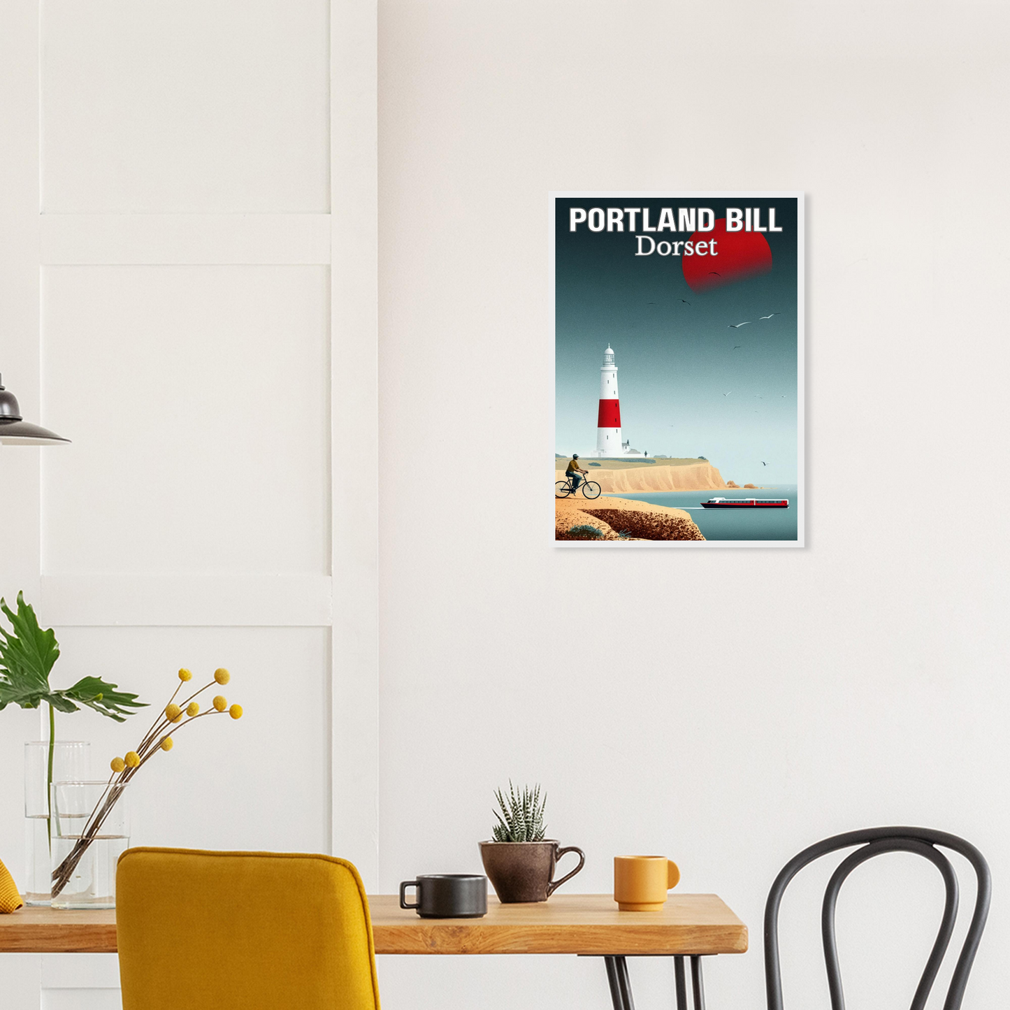 Framed poster of Portland Bill, Dorset on a wall above a table with decor items.