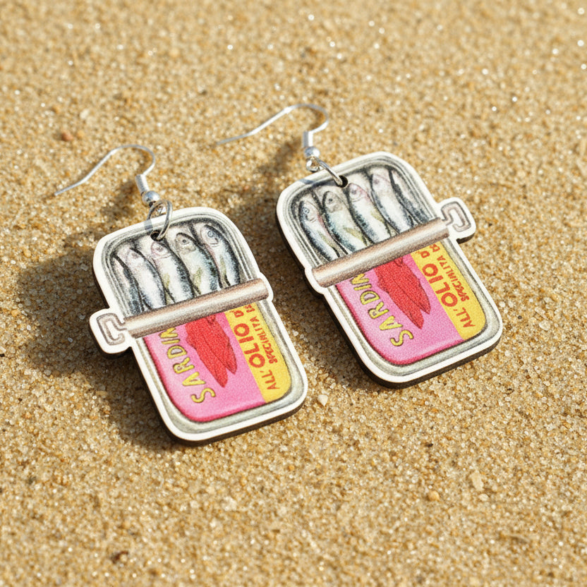 Sardine can earrings on a wooden surface