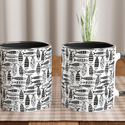 Two black and white patterned mugs on a wooden table with a plant in the background.