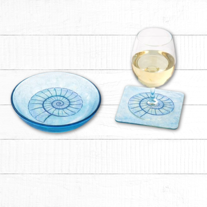 Blue coasters with spiral design on a white wooden surface with a glass of wine.