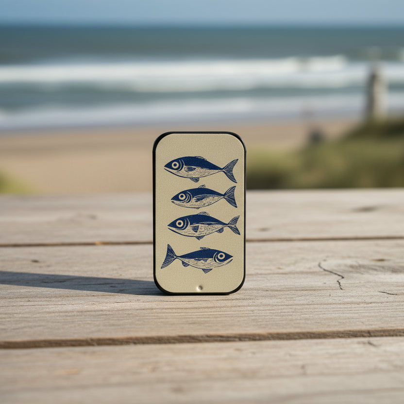 Rectangular metal tin with fish design in a coastal setting