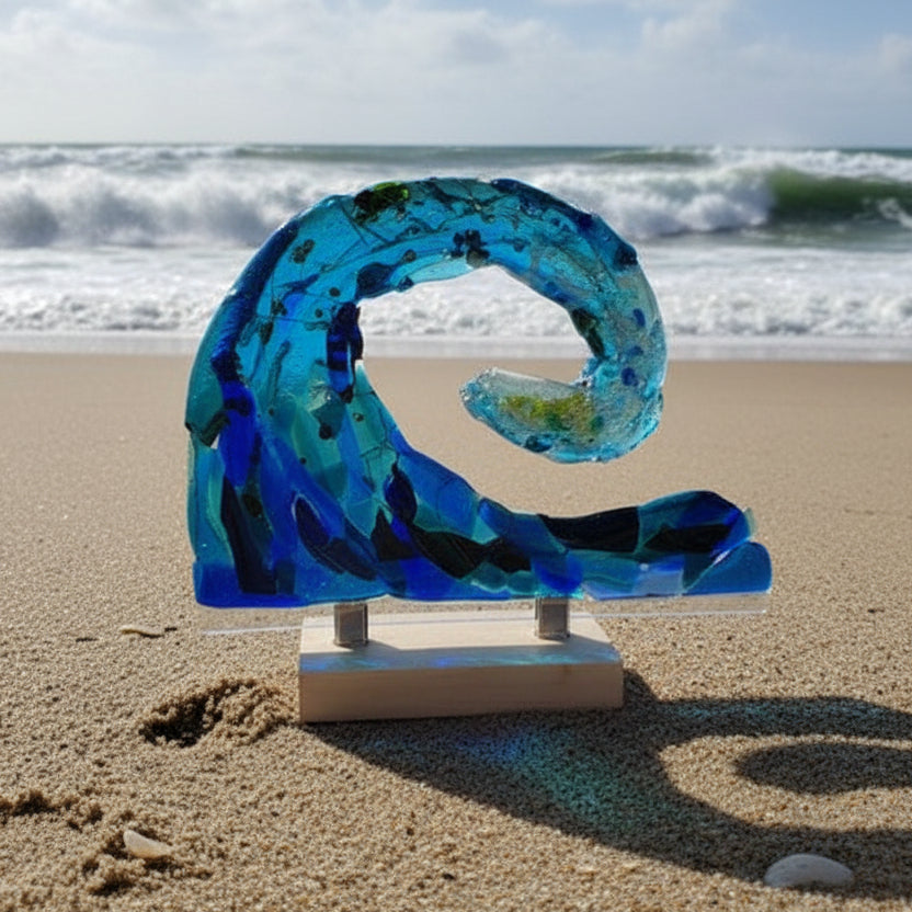 Blue glass sculpture of a wave on a white surface